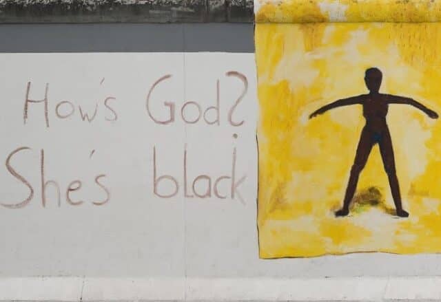 τοιχογραφία στο τείχος του Βερολίνου "How’s God? She’s black" της Christine Fuchs