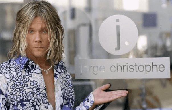 Στην εικόνα απεικονίζεται ο Jorge (Kevin Bacon) ένας κομμωτής σε πρωτοκλασάτο μαγαζί και ποζάρει μπροστά από την ταμπέλα με το όνομα του κομμωτηρίου του.
